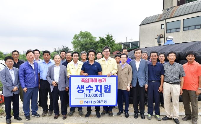 이대훈 NH농협은행장(앞줄 왼쪽 세 번째)이 9일 경기도 광명시 안터마을에 위치한 폭염피해농가를 방문해 생수 1만 병을 전달하고 기념사진을 촬영하고 있다.