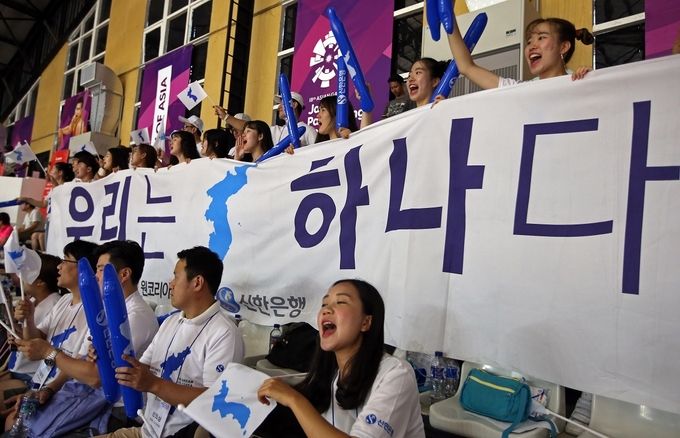 지난 20일 아시안게임 여자농구 예선경기가 열린 자카르타 겔로라 붕 카르노 농구경기장에서 신한은행이 후원하는 ‘2018 아시안게임 원코리아 공동응원단’이 북한교민들과 함께 여자농구 남북단일팀을 응원하고 있다.