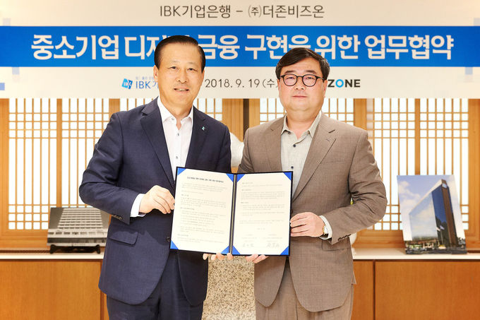 사진은 19일 을지로 기업은행 본점에서 김도진 기업은행장(왼쪽)과 김용우 더존비즈온 대표이사가 업무협약 체결식을 마치고 기념촬영을 하고 있는 모습