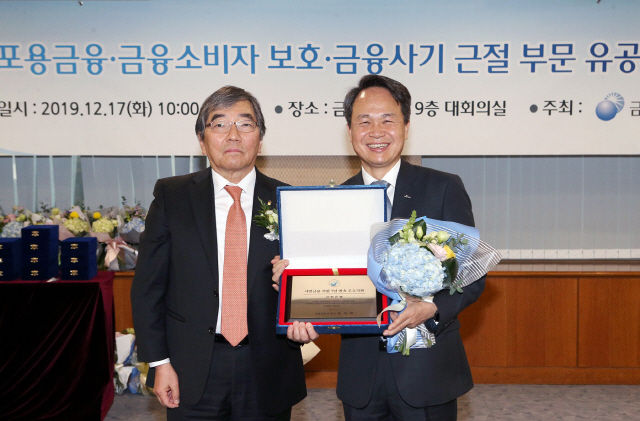 진옥동(오른쪽) 신한은행장이 17일 서울 여의도 금융감독원에서 열린 ‘2019 포용금융·금융소비자보호·금융사기근절 부문 등 유공자 시상식’에서 ‘서민금융 지원 7년 연속 우수기관’으로 선정돼 윤석헌 금감원장으로부터 감사패를 받고 있다. /사진제공=신한은행