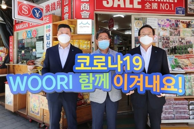 손태승 우리금융그룹 회장(사진 오른쪽)과 권광석 우리은행장(사진 왼쪽)이 서울 중구 소재 남대문시장에서 물품구매 후 박칠복 남대문시장 남산상회 대표와 코로나19 극복을 다짐하며 기념촬영을 하고 있다. 