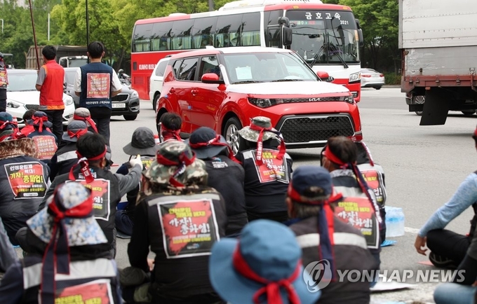 민주노총 공공운수노조 화물연대본부(이하 화물연대) 총파업 나흘째인 10일 오후 광주 서구 기아차 생산 공장 앞에서 카캐리어를 동원하지 못해 개별 운송하는 번호판 없는 완성차량이 화물연대 노조원들의 결의대회 장소를 지나가고 있다. 제공=연합뉴스