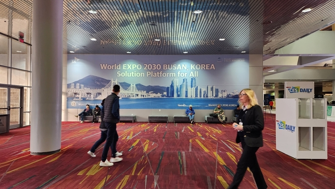 ‘2030 부산엑스포 유치 기원’ 대형 현수막이 게시된 CES 2023 행사장인 美 라스베이거스 컨벤션 센터안에서 관람객들이 지나가고 있다.(사진=SK이노베이션)