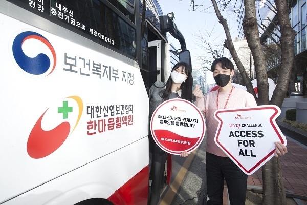 SK디스커버리와 계열사 구성원이 세계 혈우인의 날을 맞이해 혈우인을 응원하는 팻말을 들고 레드타이 챌린지를 진행하고 있다.(사진=SK디스커버리)