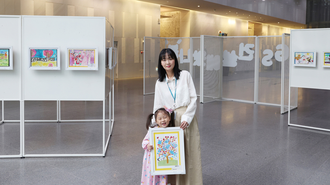 서울 종로구에 위치한 GS건설 본사 사옥 1층에서 진행된 ‘GS건설에 왔나 봄’ 그림전시전에서 임직원이 자녀와 관람하고 있는 사진 (사진=GS건설 제공)