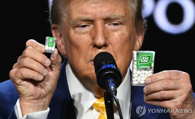 미국 공화당 대선후보인 트럼프 전 대통령이 6일(현지시간) 애리조나주 피닉스 드림시티 교회에서 열린 타운홀 미팅에서 IRA(인플레이션 감축법) 결과를 설명하기 위해 크고 작은 크기의 틱택 민트 캔디를 들어 보이고 있다.(사진=연합뉴스)