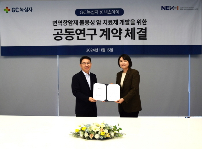 정재욱 GC녹십자 R&D 부문장(왼쪽)과 윤경완 넥스아이 대표가 협약서에 서명하고 기념촬영을 하고 있다. 